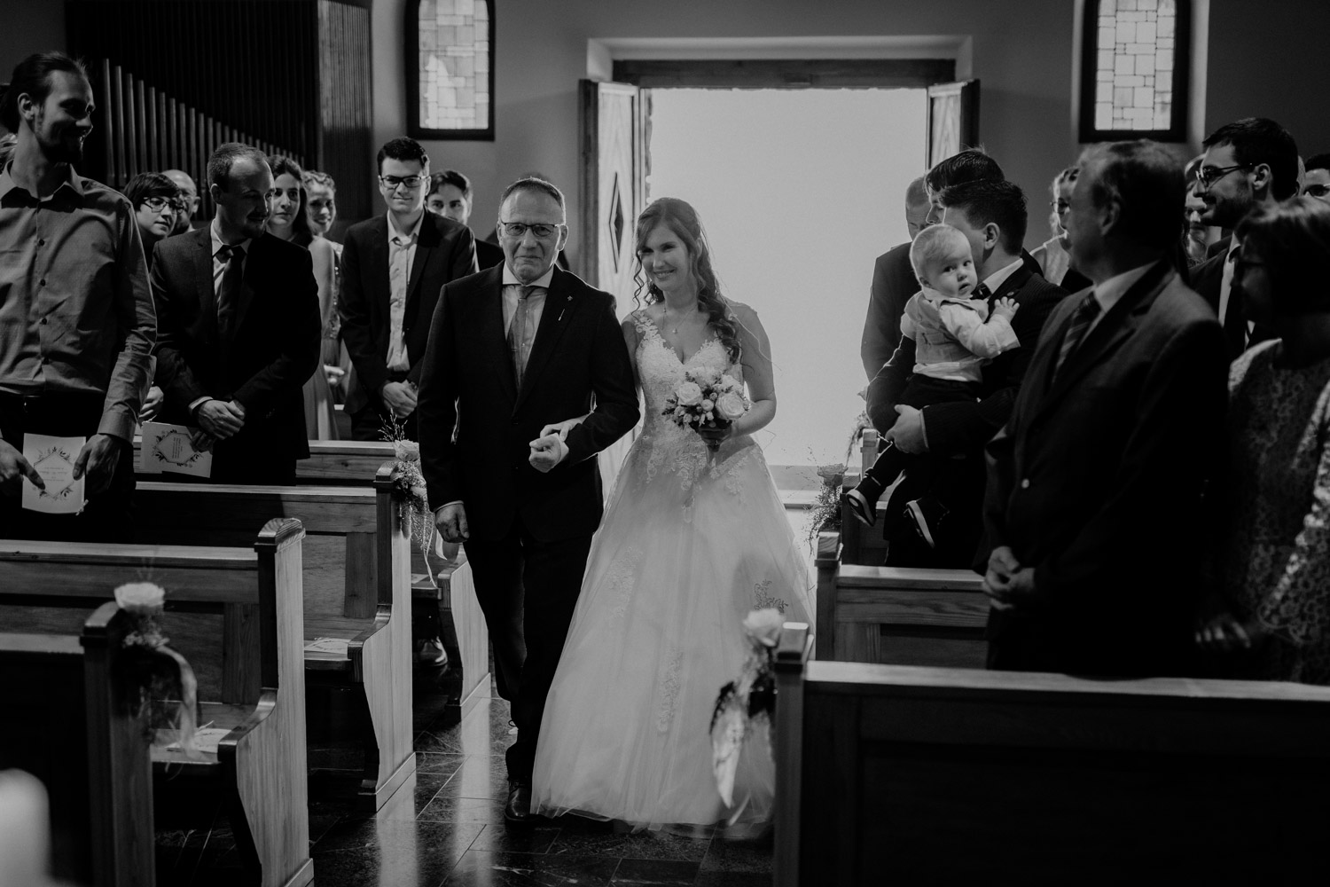 Hochzeitsfotograf in der Marienkapelle in Morschach Schweiz Hochzeitsfotografin kirchliche Trauung Schweizer Berge Alpen natürliche Hochzeitsfotografie Braut Brautvater Einzug