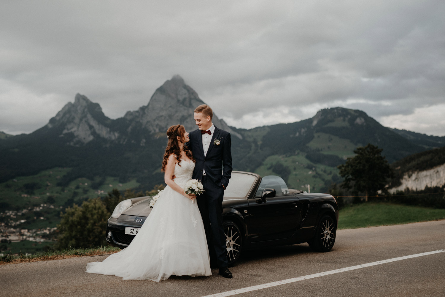 Hochzeitsfotograf in der Marienkapelle in Morschach Schweiz Hochzeitsfotografin kirchliche Trauung Schweizer Berge Alpen natürliche Hochzeitsfotografie Brautpaarshooting in den Bergen natürliche ungestellte Hochzeitsreportage Cabriolet Auto