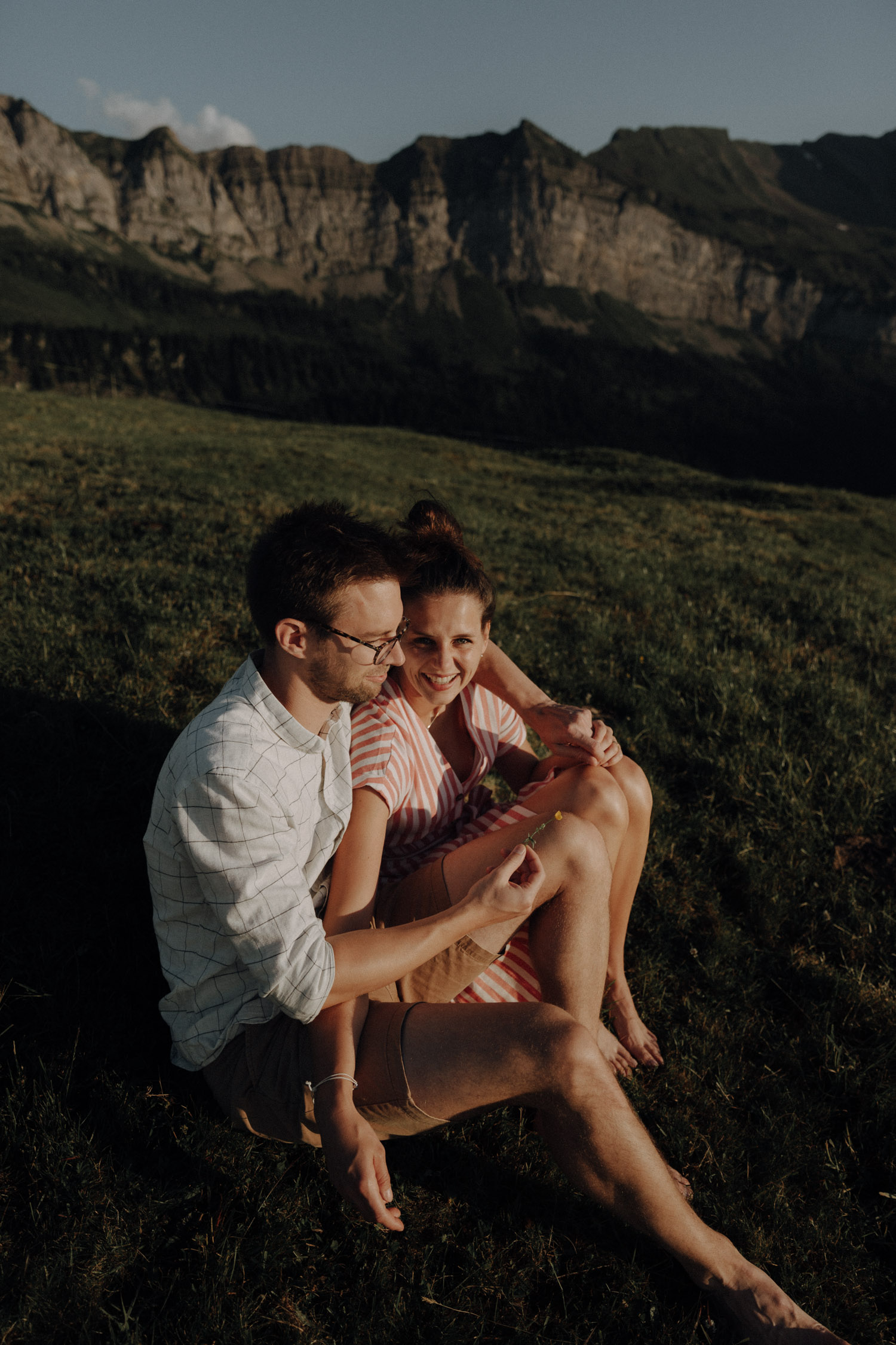 Swiss elopement photographer portrait of a couple sitting on a meadow in the Swiss alps