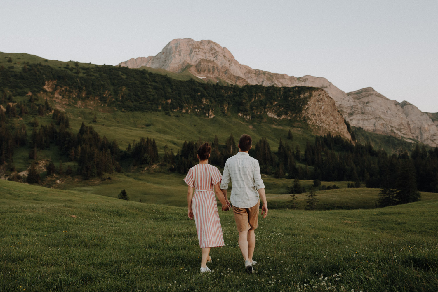 Couple walking over a meadow in the Swiss alps photographed by Swiss elopement photographer