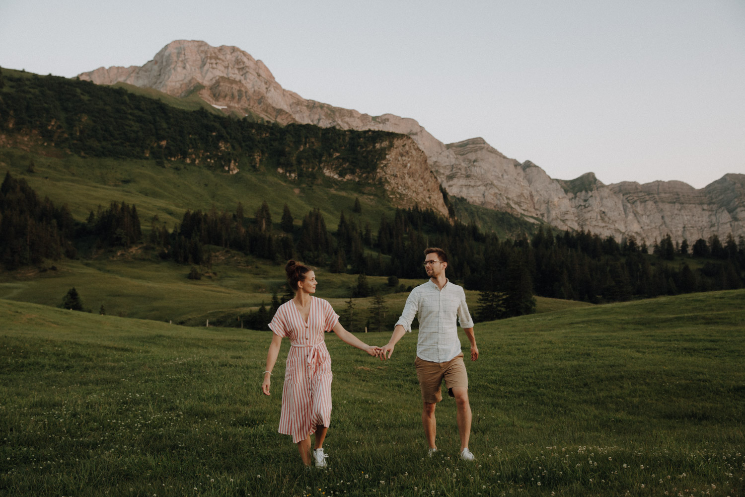 Couple walking over a meadow in the Swiss alps photographed by Swiss elopement photographer