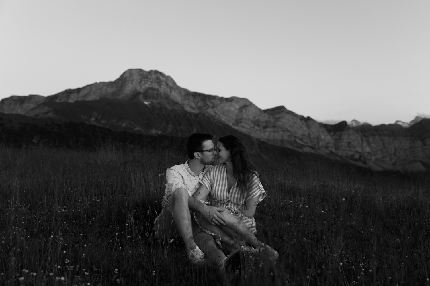 Couple sitting on a meadow in the Swiss mountains photographed by best Swiss wedding photographer