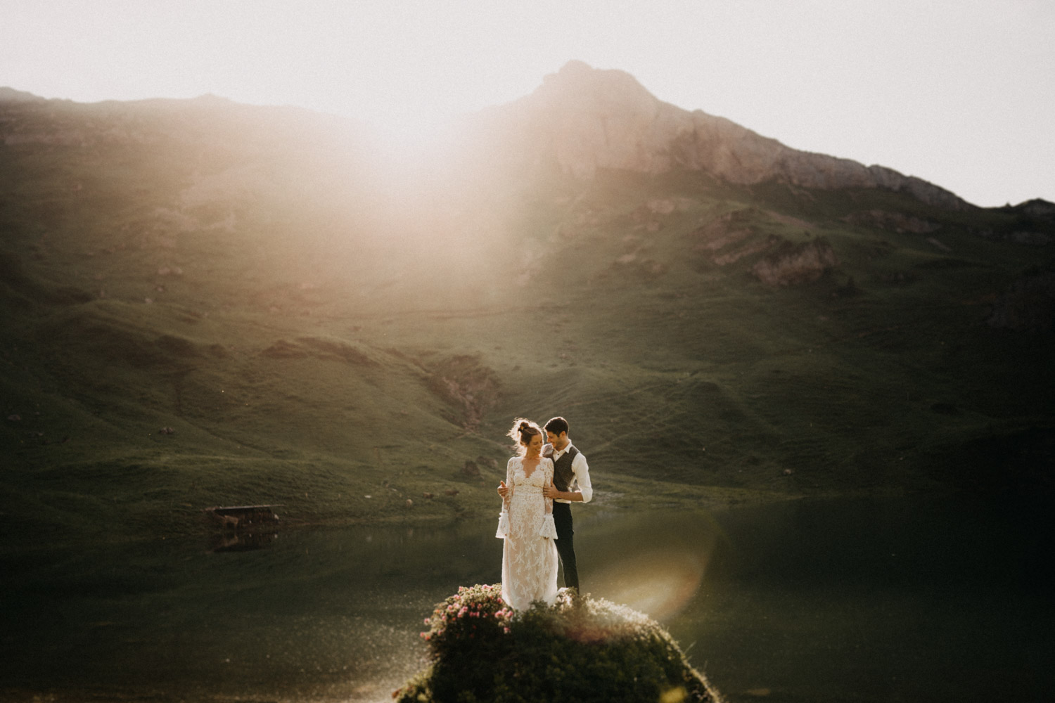 Brautpaar steht auf einem Felsen in Abendsonne an einem Bergsee Schweizer Hochzeitsfotografin
