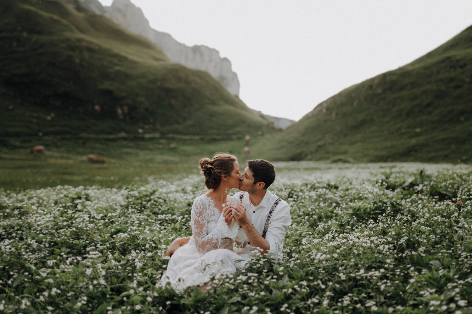 Brautpaar auf einer Wiese mit weissen Blumen in den Schweizer Bergen Alpen