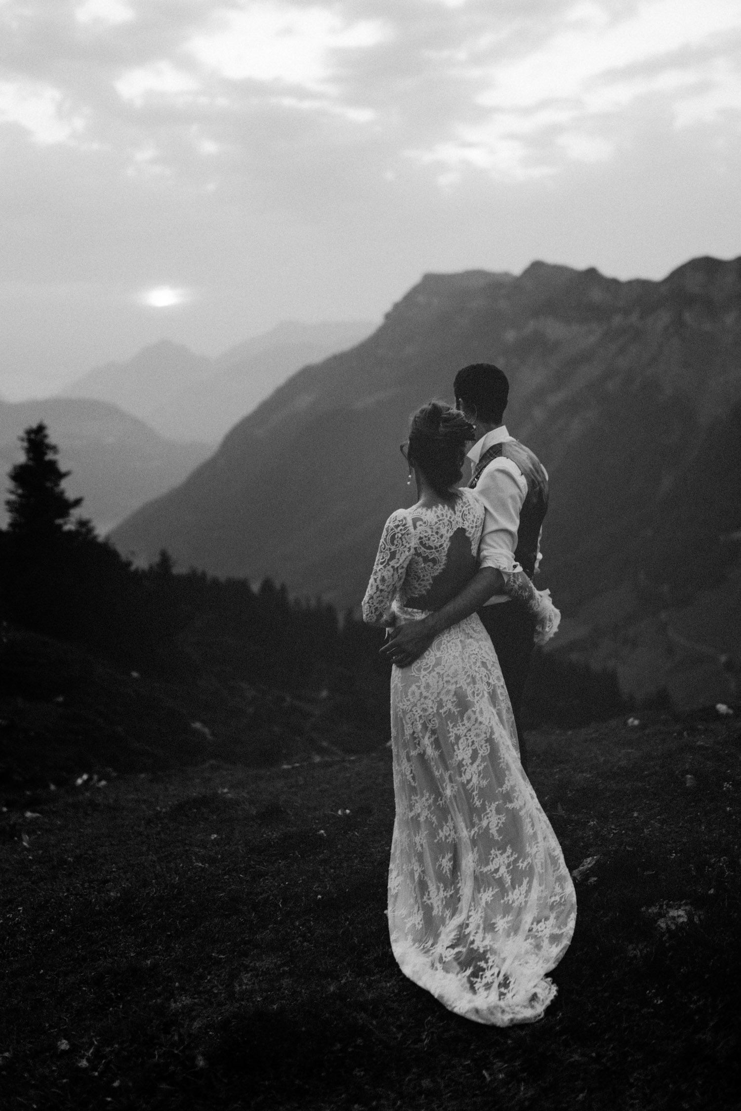 Brautpaar schaut den Mond an in den Schweizer Bergen in schwarz-weiss Sonnenuntergang